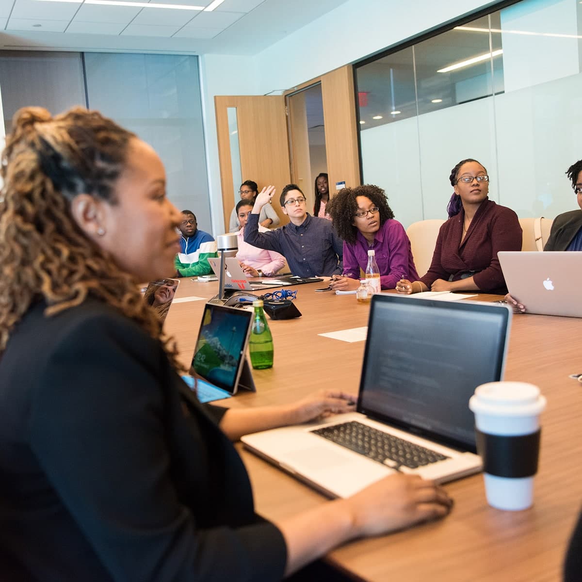 collaborations-shiftbox-meeting A group of diverse people sitting around a large table in a boardroom looking at a presentation