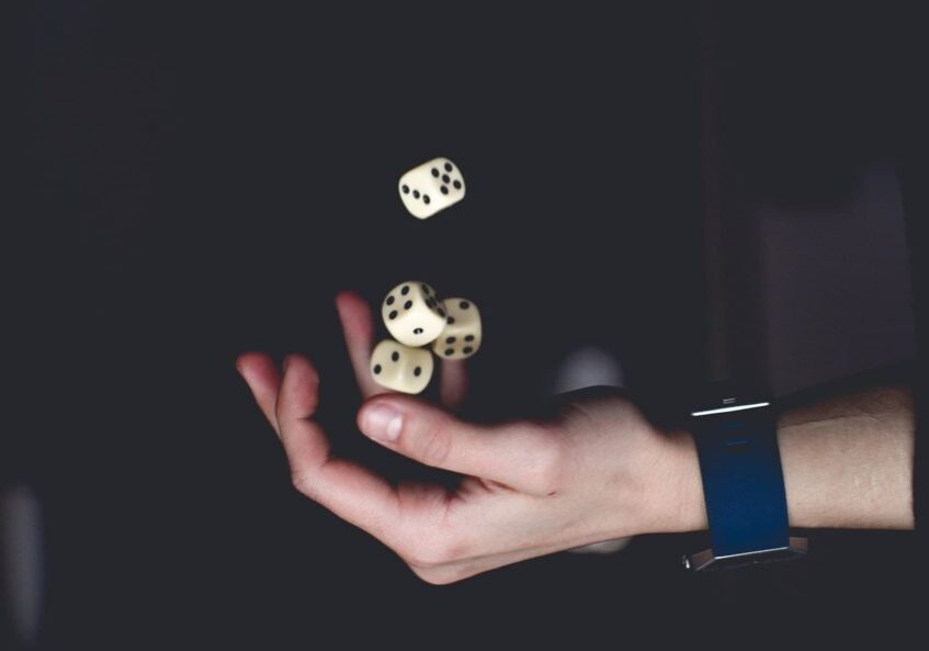 A hand juggling four dice against a black background